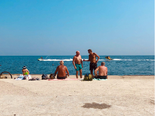 several older people relaxing on a sunny beach. 