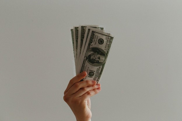 a hand holds up several hundred dollar bills
