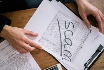 Money looking paperwork with ‘scam’ written across it in black marker