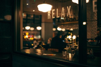 A view into a coffee shop window, a sign hangs saying ‘relax’