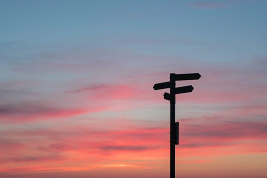 Road signs in shadow against a sunset