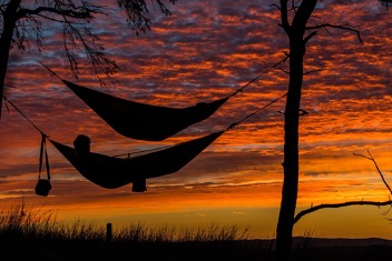 Two hammocks hang against an orange sunset sky Wealth Building 