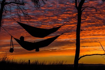 Two hammocks hang against an orange sunset sky Wealth Building