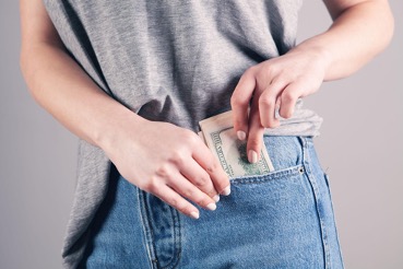Person sliding a stack of hundred dollar bills into a jean pocket Investing in the Future