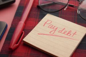 A post-it note with ‘pay debt’ written on in red ink