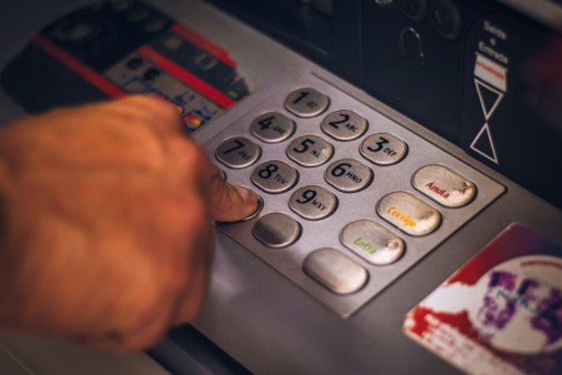Close-up of a hand pressing numbers on an ATM Bank Deposits