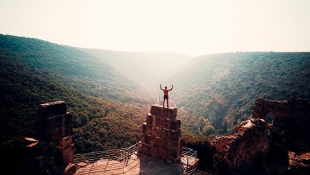 Zoomed out view of a man on top of a tower overlooking a valley.