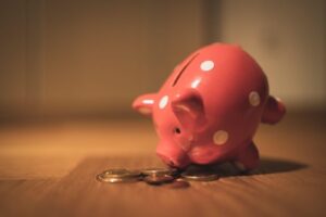 A pink porcelain piggy bank next to some coins on the floor Alternative Investments