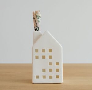 A house-shaped model with money unfurling from the chimney for ‘Demystifying Accredited Investor Investments- What You Need to Know’