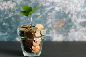 Interior, a drinking glass full of coins with a bright green sapling bursting through the top, for “How Our Equity Raise Is Driving Growth”