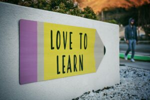 A pencil shaped sign reading Love to Learn, for “How to Use Alternative Assets to Grow Wealth in Your 30s”