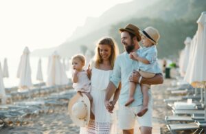 Exterior, a young family walking across a sandy beach, for “How Dual-Income Families Can Balance Busy Lives and Financial Growth”